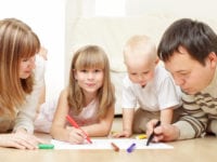 Parents with children drawing laying on a floor
